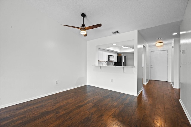 unfurnished living room featuring ceiling fan, dark hardwood / wood-style floors, and a textured ceiling