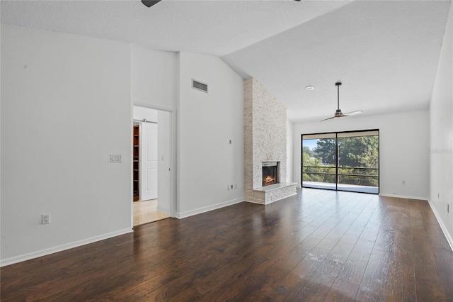 unfurnished living room with hardwood / wood-style flooring, a textured ceiling, a barn door, ceiling fan, and a fireplace