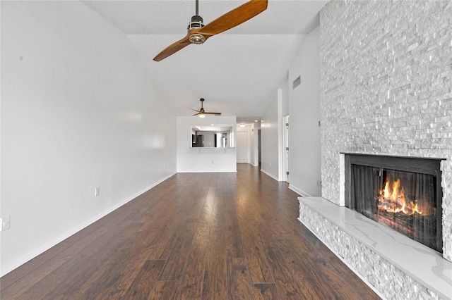 unfurnished living room featuring a stone fireplace, high vaulted ceiling, dark hardwood / wood-style floors, and ceiling fan