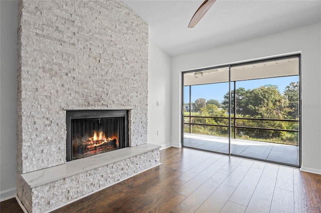 unfurnished living room with dark wood-type flooring, a textured ceiling, vaulted ceiling, and a fireplace