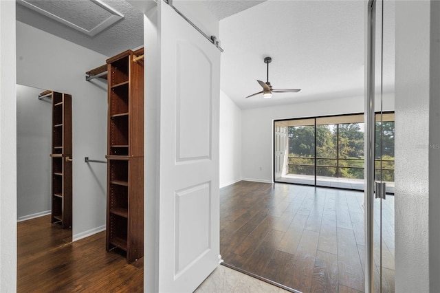 interior space with a barn door, dark hardwood / wood-style floors, and ceiling fan