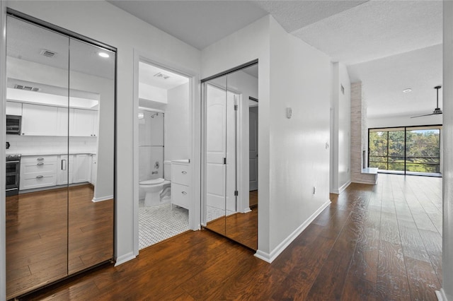 corridor with wood-type flooring, a textured ceiling, and lofted ceiling