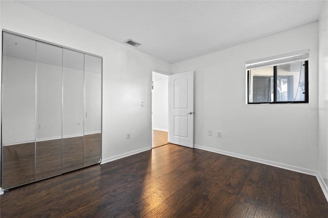 unfurnished bedroom with dark hardwood / wood-style floors and a closet