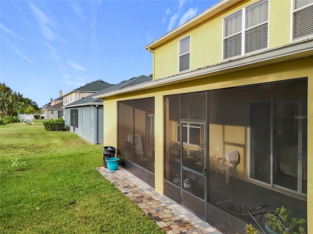 rear view of house featuring a sunroom and a yard