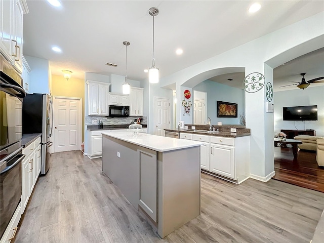 kitchen featuring pendant lighting, white cabinetry, black appliances, and light hardwood / wood-style flooring