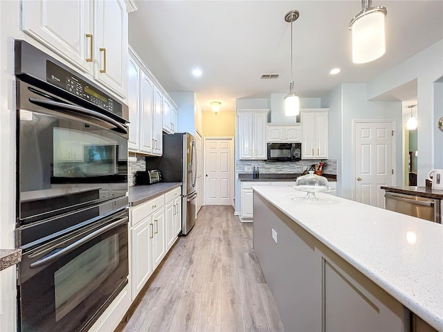 kitchen featuring pendant lighting, black appliances, white cabinets, and backsplash