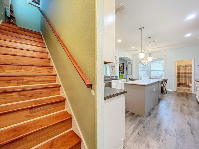 stairs featuring wood-type flooring, sink, and a notable chandelier