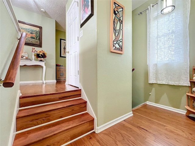 stairs featuring wood-type flooring and a textured ceiling