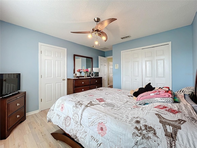 bedroom with a closet, light wood-type flooring, a textured ceiling, and ceiling fan