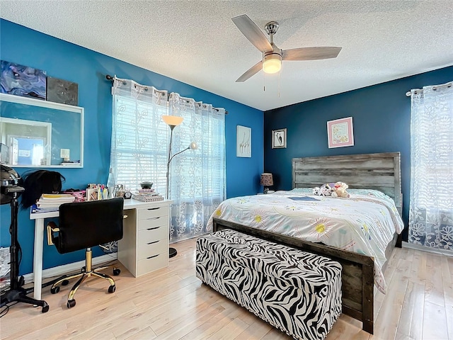 bedroom with a textured ceiling, light hardwood / wood-style floors, and ceiling fan