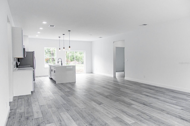 unfurnished living room featuring sink and light hardwood / wood-style flooring