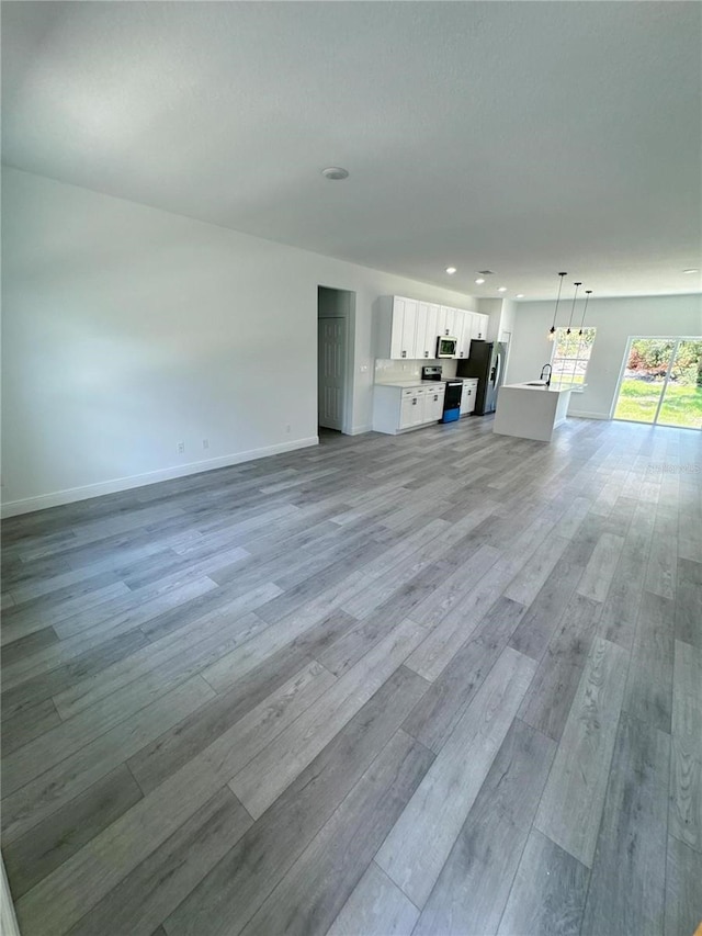 unfurnished living room with light hardwood / wood-style floors and sink