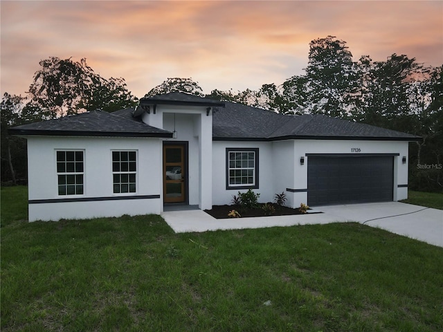 view of front of home with a garage and a lawn