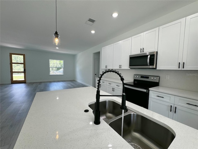 kitchen with appliances with stainless steel finishes, dark hardwood / wood-style floors, pendant lighting, light stone countertops, and white cabinets