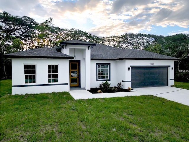 view of front facade with driveway, a shingled roof, an attached garage, a front yard, and stucco siding