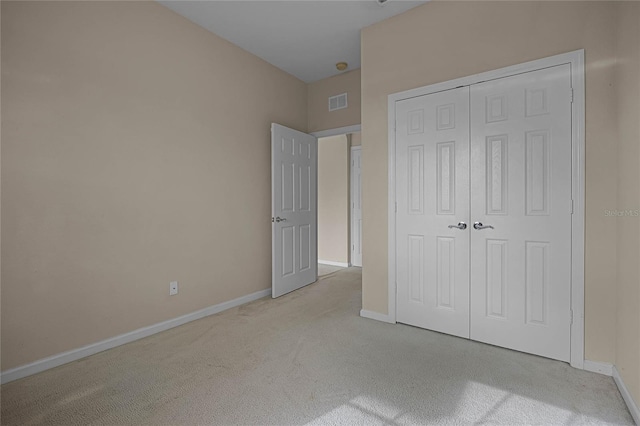 unfurnished bedroom featuring a closet and light colored carpet