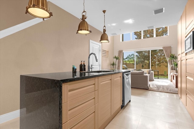 kitchen with dishwasher, sink, light brown cabinets, pendant lighting, and a center island with sink