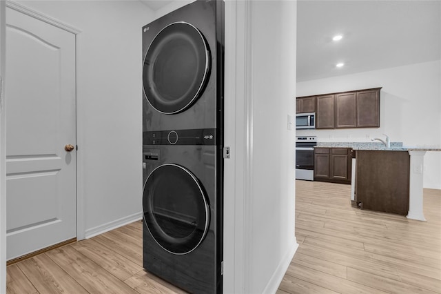 washroom with stacked washer / drying machine and light wood-type flooring