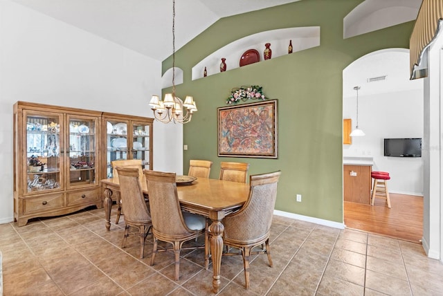 tiled dining area featuring a notable chandelier and high vaulted ceiling