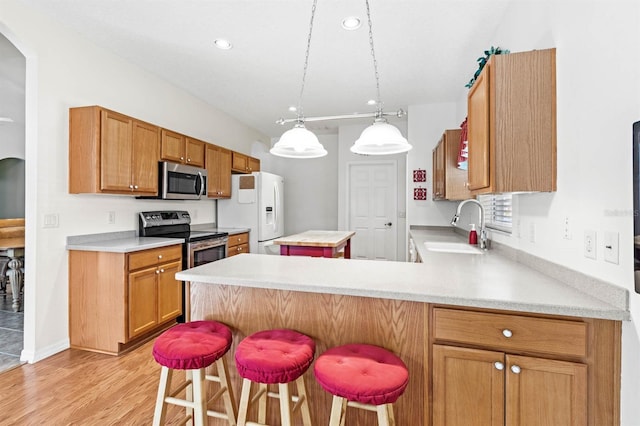 kitchen featuring a kitchen breakfast bar, sink, light hardwood / wood-style flooring, appliances with stainless steel finishes, and kitchen peninsula