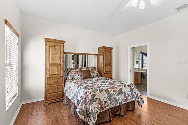 bedroom with ceiling fan, wood-type flooring, connected bathroom, and multiple windows