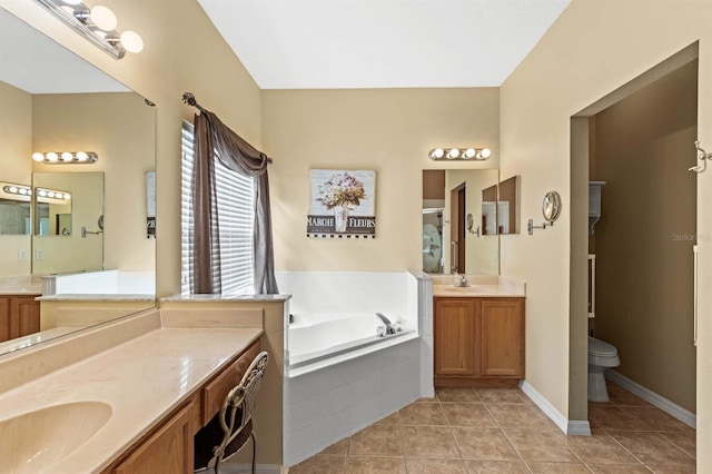 bathroom featuring toilet, vanity, a relaxing tiled tub, and tile patterned floors