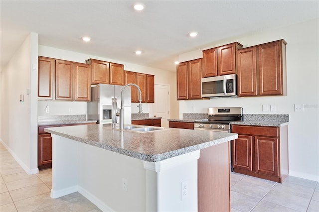 kitchen featuring light tile patterned floors, sink, a kitchen island with sink, and appliances with stainless steel finishes