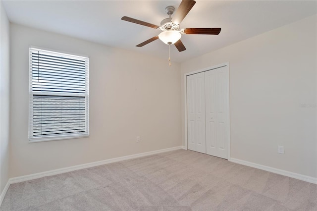 unfurnished bedroom with ceiling fan, light carpet, and a closet