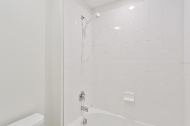 bathroom with tiled shower / bath and toilet