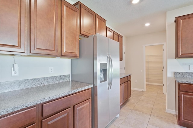 kitchen with a textured ceiling, stainless steel refrigerator with ice dispenser, and light tile patterned floors