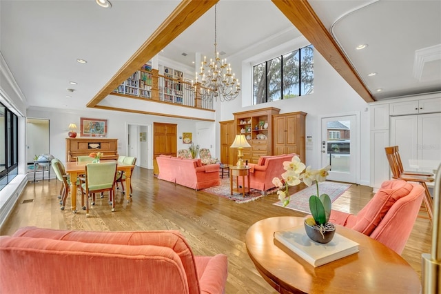 interior space featuring ornamental molding, a towering ceiling, light wood-type flooring, and an inviting chandelier