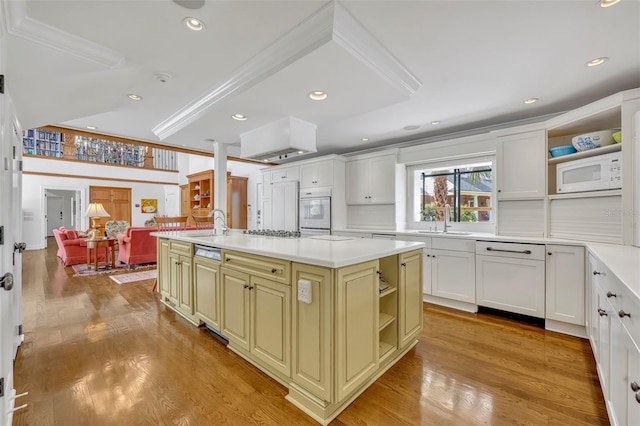 kitchen with light hardwood / wood-style floors, white appliances, sink, and a center island with sink