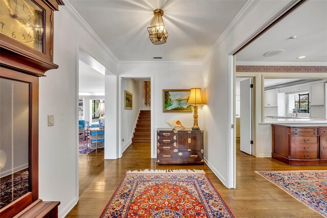 corridor with light wood-type flooring and crown molding