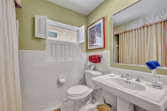 bathroom with tile patterned flooring, toilet, and tile walls