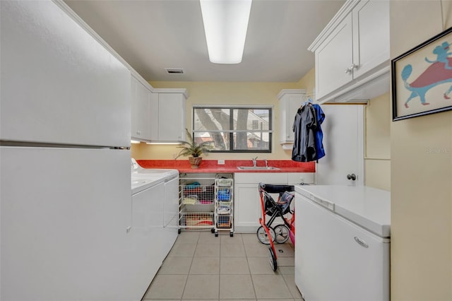 clothes washing area featuring washing machine and dryer, cabinets, sink, and light tile patterned floors