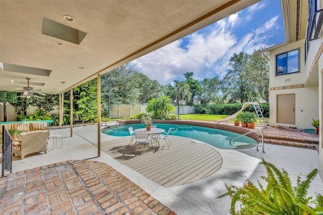 view of swimming pool with a water slide, ceiling fan, and a patio