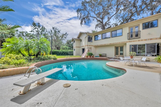 view of pool with a water slide, french doors, a patio, and a diving board