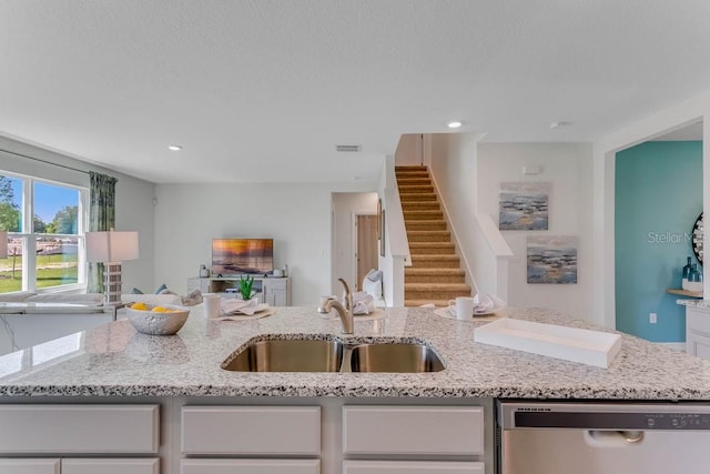 kitchen with white cabinetry, sink, light stone counters, and dishwasher