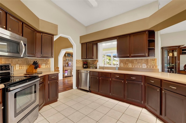 kitchen with light tile patterned floors, stainless steel appliances, tasteful backsplash, and sink