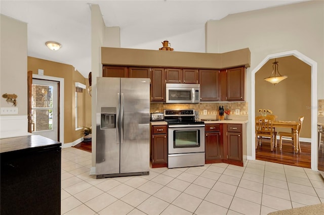 kitchen with decorative backsplash, light tile patterned floors, hanging light fixtures, and appliances with stainless steel finishes