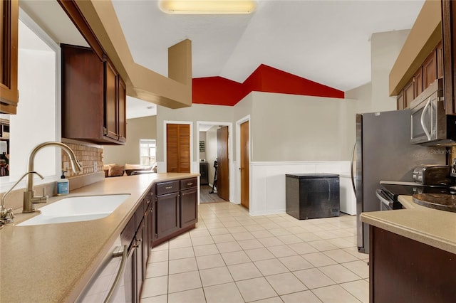 kitchen featuring sink, vaulted ceiling, decorative backsplash, light tile patterned flooring, and appliances with stainless steel finishes