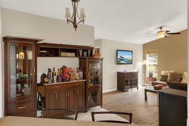 living room featuring ceiling fan with notable chandelier, vaulted ceiling, and light wood-type flooring