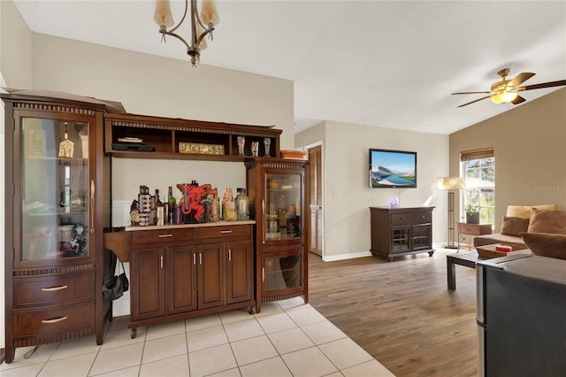 interior space with ceiling fan with notable chandelier, light wood-type flooring, and vaulted ceiling