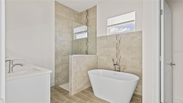 bathroom with tile walls, vanity, and separate shower and tub