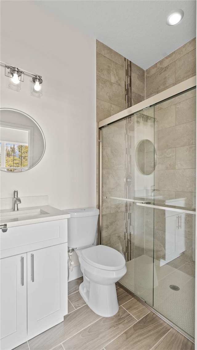 bathroom featuring walk in shower, vanity, and toilet