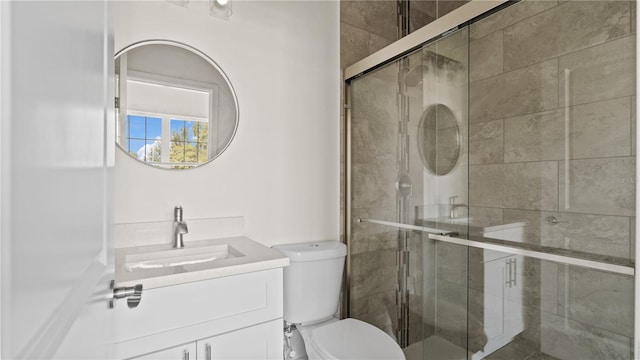 bathroom with vanity, toilet, and a shower with door