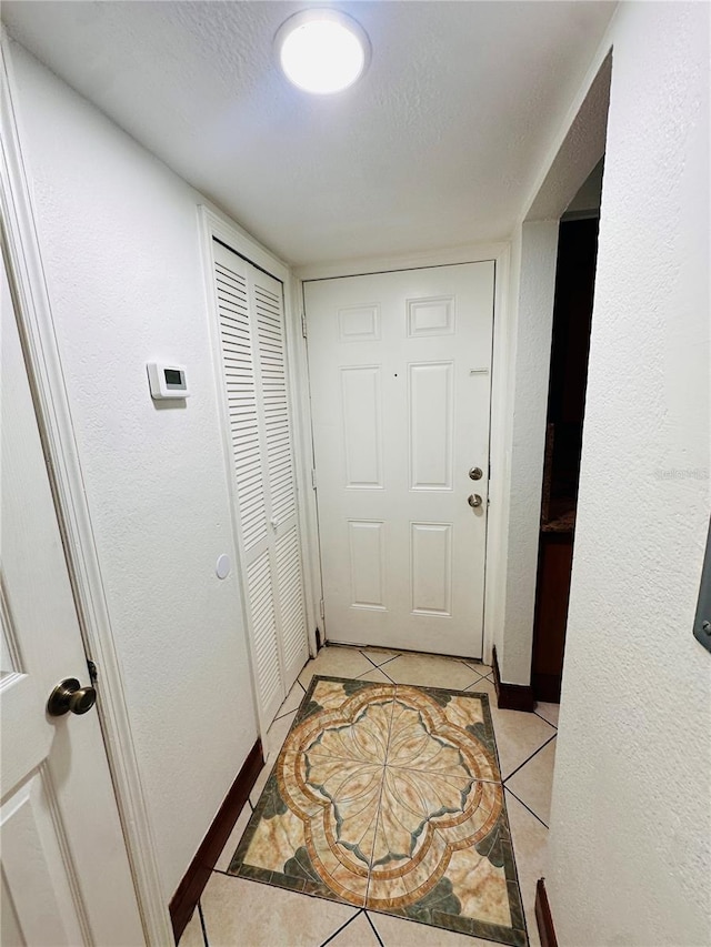 doorway to outside with light tile patterned flooring and a textured ceiling