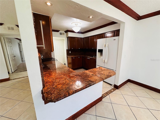 kitchen featuring white fridge with ice dispenser, a textured ceiling, dark stone countertops, and light tile patterned floors