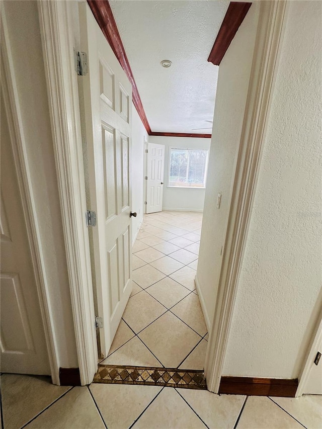 hallway with lofted ceiling, a textured ceiling, and light tile patterned flooring