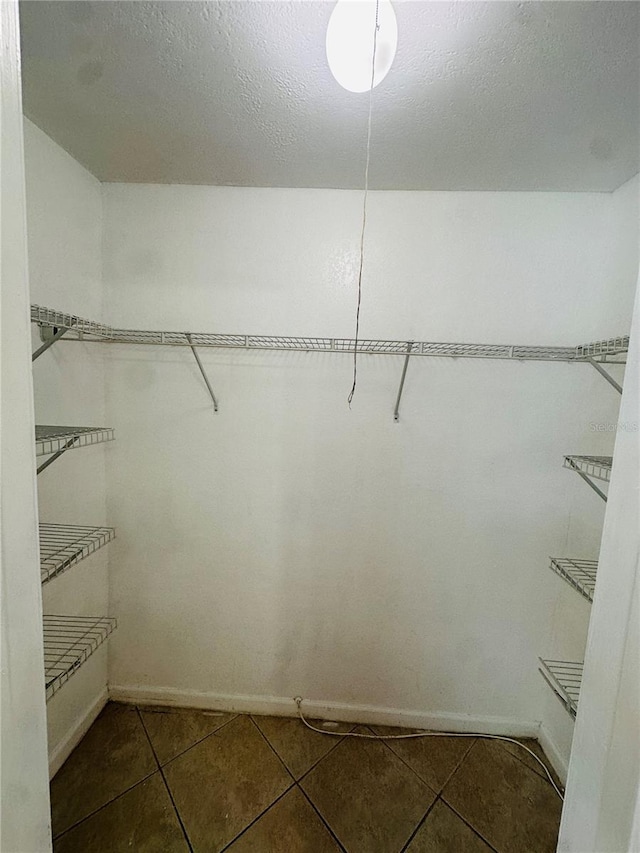 spacious closet featuring dark tile patterned flooring